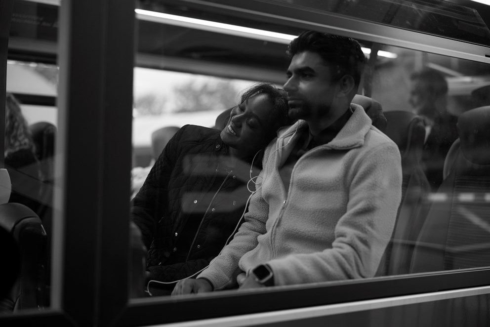 A couple travelling on a bus, looking happy.